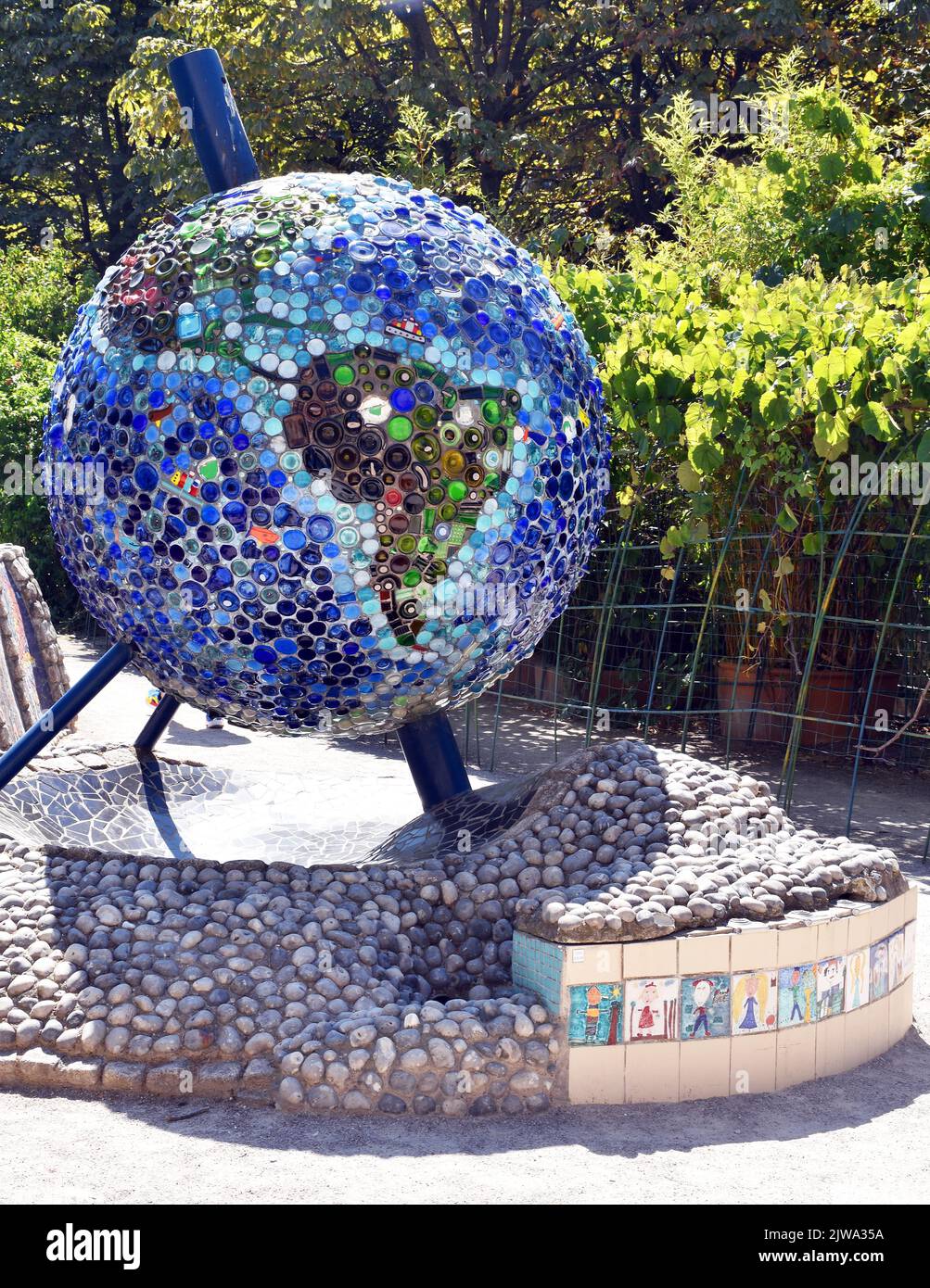 A beautiful Globe of the Earth, on stout tripod, covered in multi-coloured glass, marbles, mosaic etc in a small Terrain d’Aventure, for 2-4 year olds Stock Photo