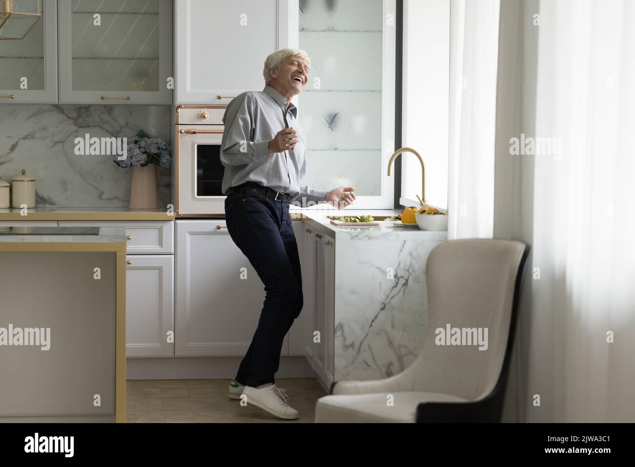 Cheerful energetic senior man having fun in modern kitchen interior Stock Photo
