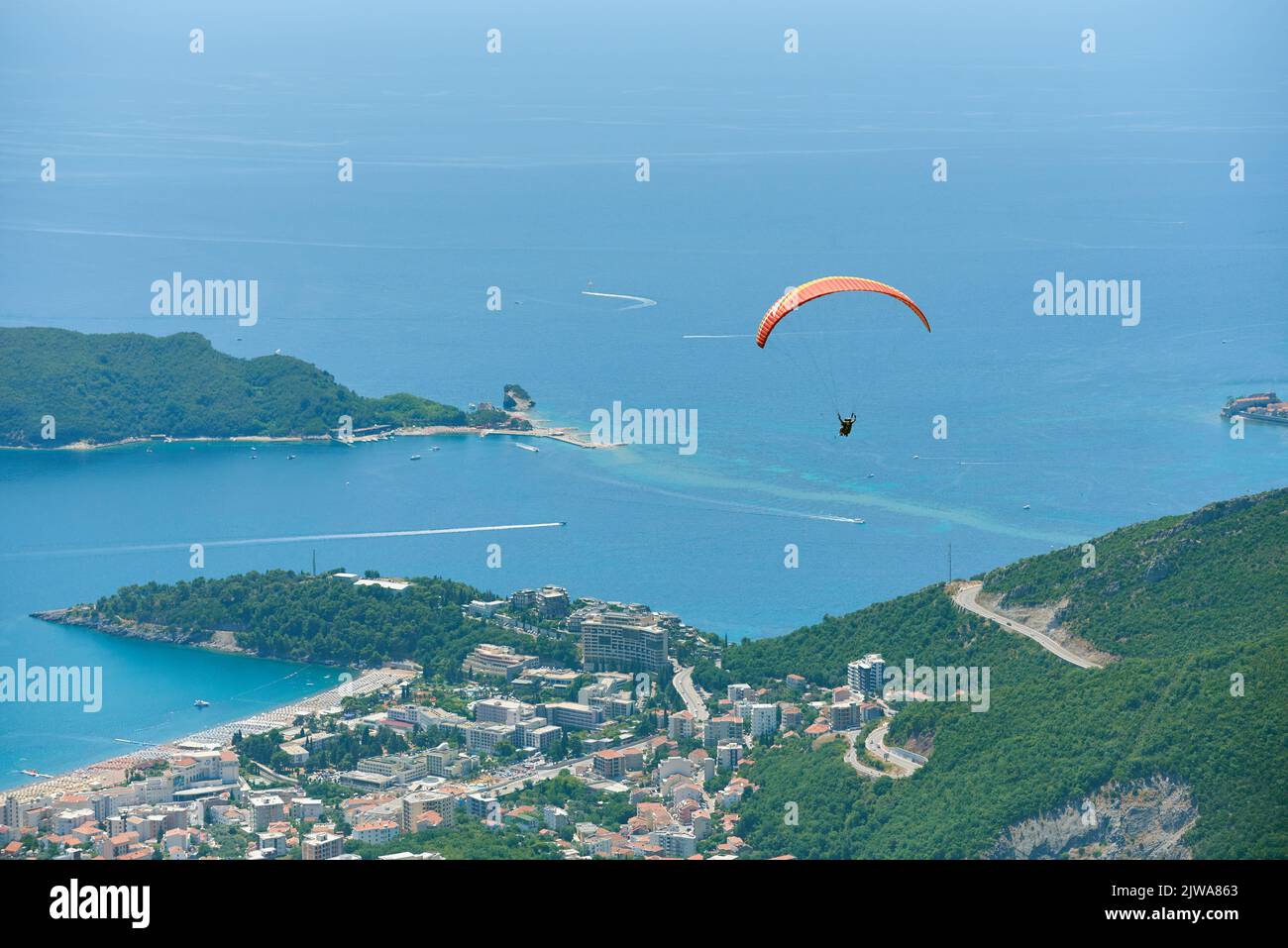 Paragliding tandem with tourist above city of Budva, Montenegro Stock Photo