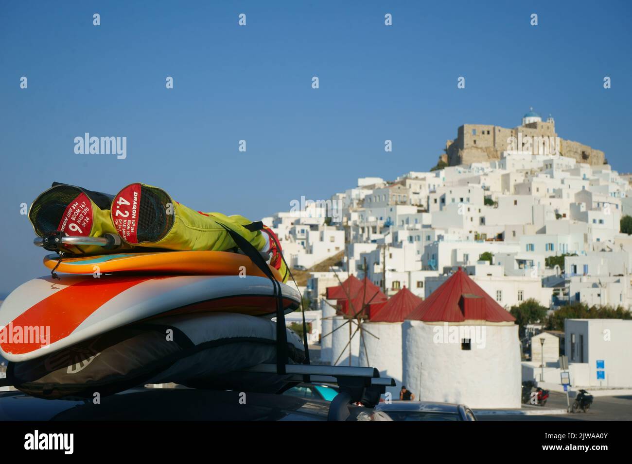 Traditional Greece - Chora village with windmills. Astypalea island, Dodecanese, summer - car carring surfboard Stock Photo