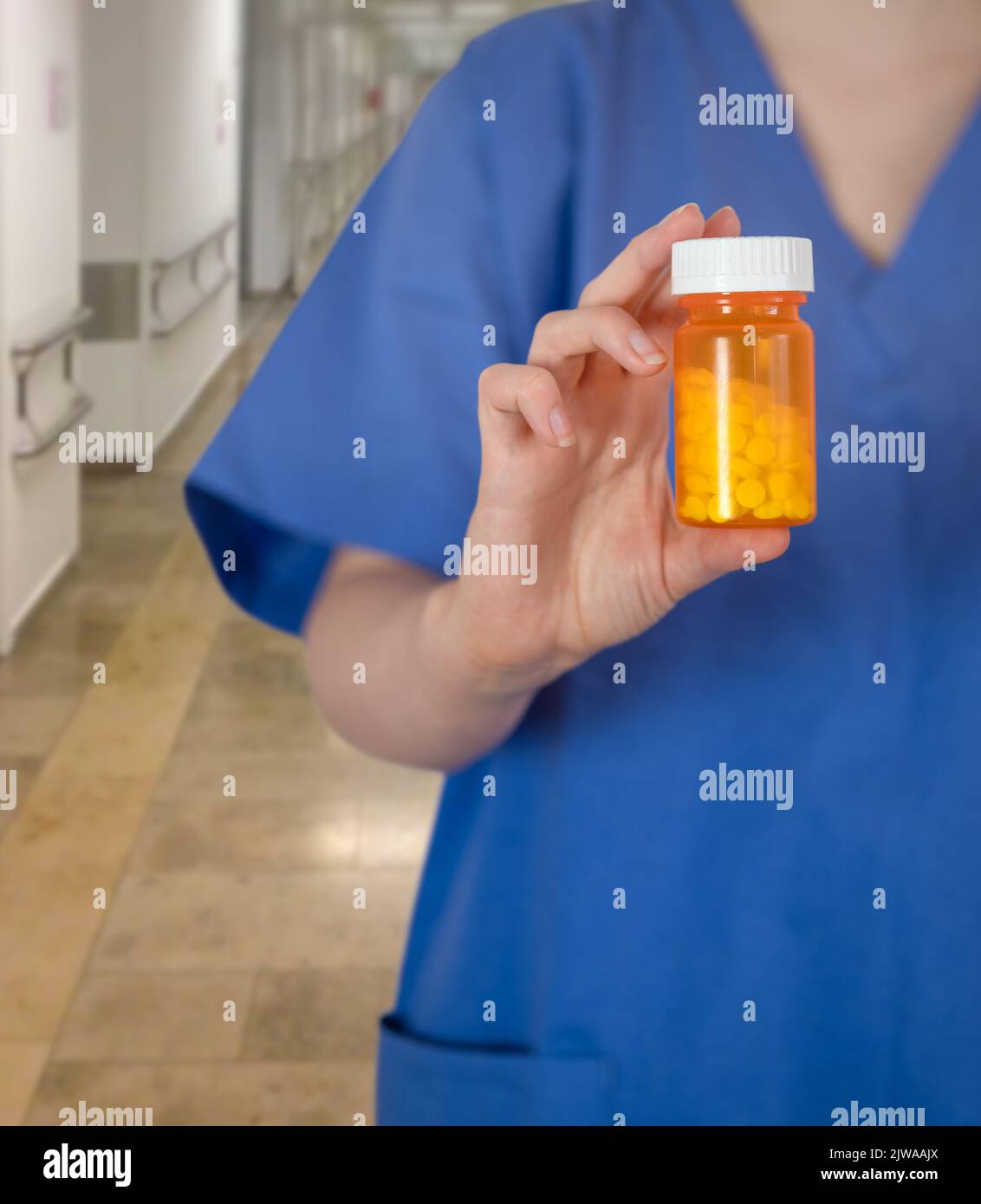 A Young Doctor Or Nurse In Medical Scrubs Holding A Prescription Bottle Of Medication In A Hospital Corridor Stock Photo