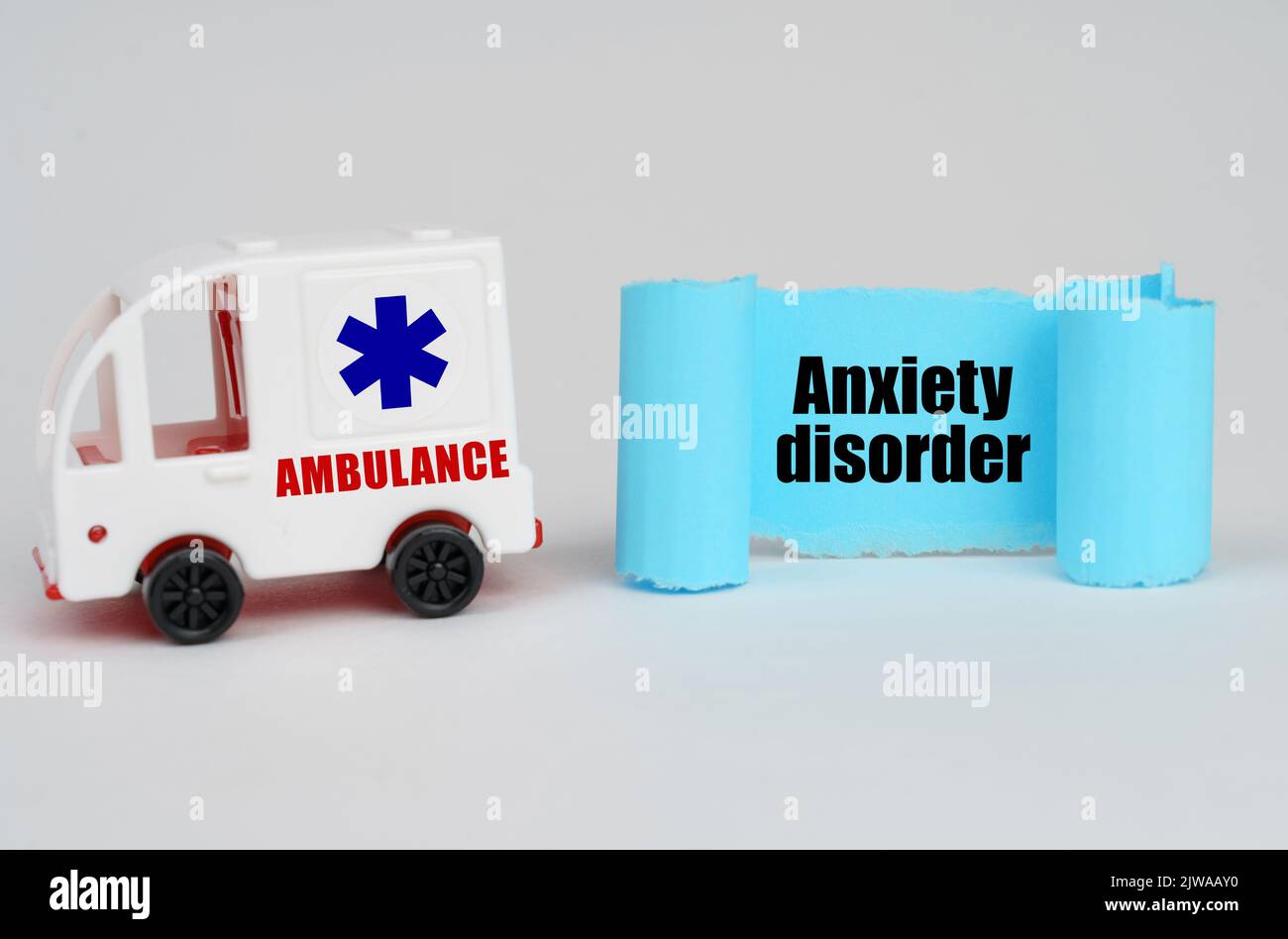 On a white surface, an ambulance and a blue paper sign with the inscription - Anxiety disorder Stock Photo
