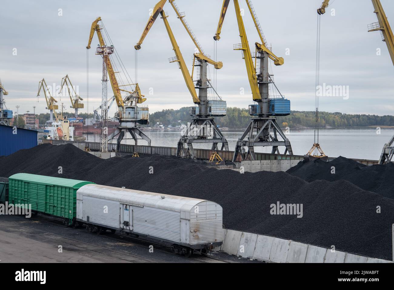 Loading coal anthracite into the railway freight wagons in port with crane bucket Stock Photo