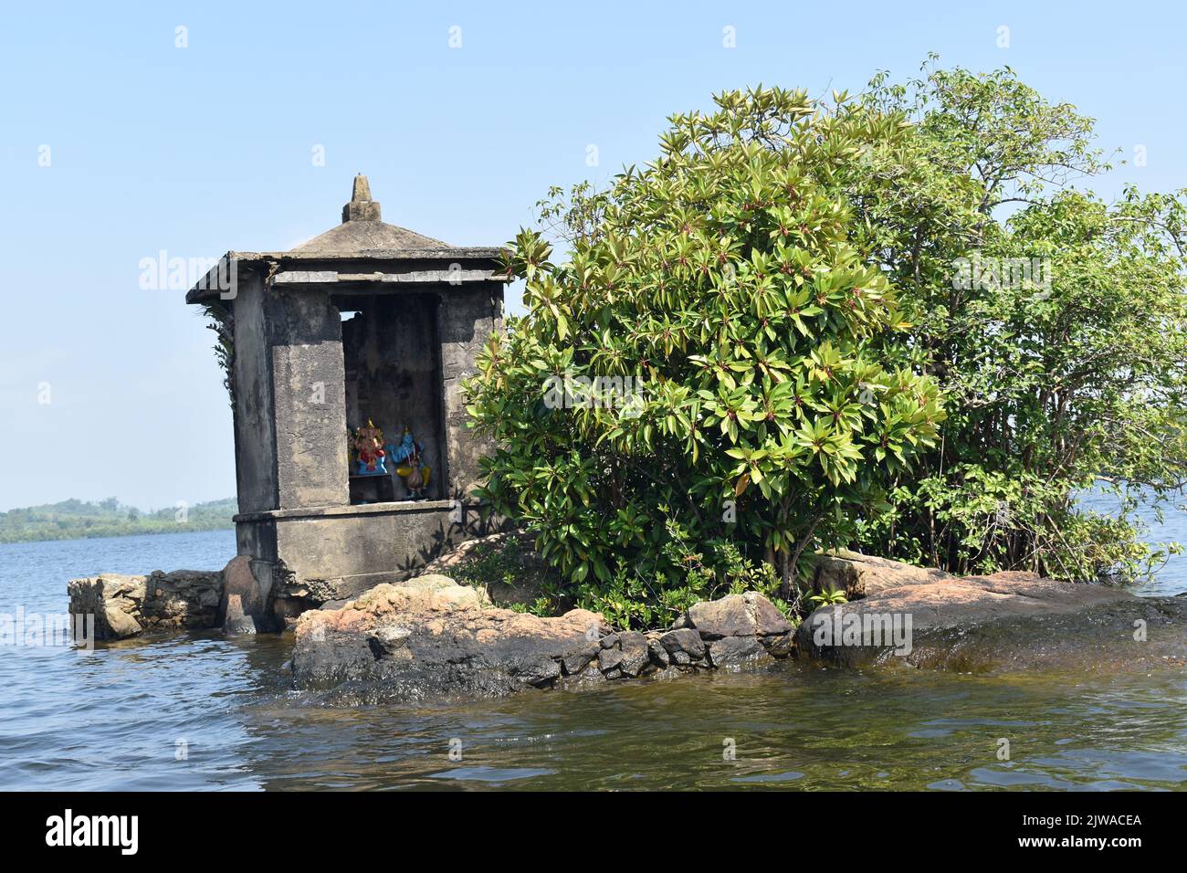 The smallest islet in Madu Ganga Lake is called “Satha Paha Doowa”. “Paha” translates to “five”, whereas “Satha” means “cent”. According to local tradition, the islet had once been purchased for five cents. But others say, it got its name due to the shape or small size which resembles just a small coin. Nontheless Fice-Cent-Island is big enough to carry a temple. The shrine is dedicated to Kataragama, a deity revered by Sinhalese Buddhists and Tamil Hindus and Weddah animists alike. In a way, it’s a Devale, a Buddhist shrine for a Hindu deity. Sri Lanka. Stock Photo