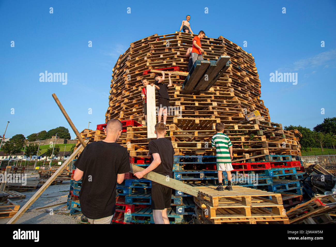 Kids stack pallets over the weekend in preparation for the bonfire marking a Catholic feast day of the Assumption of the Virgin Mary in the Bogside . Stock Photo