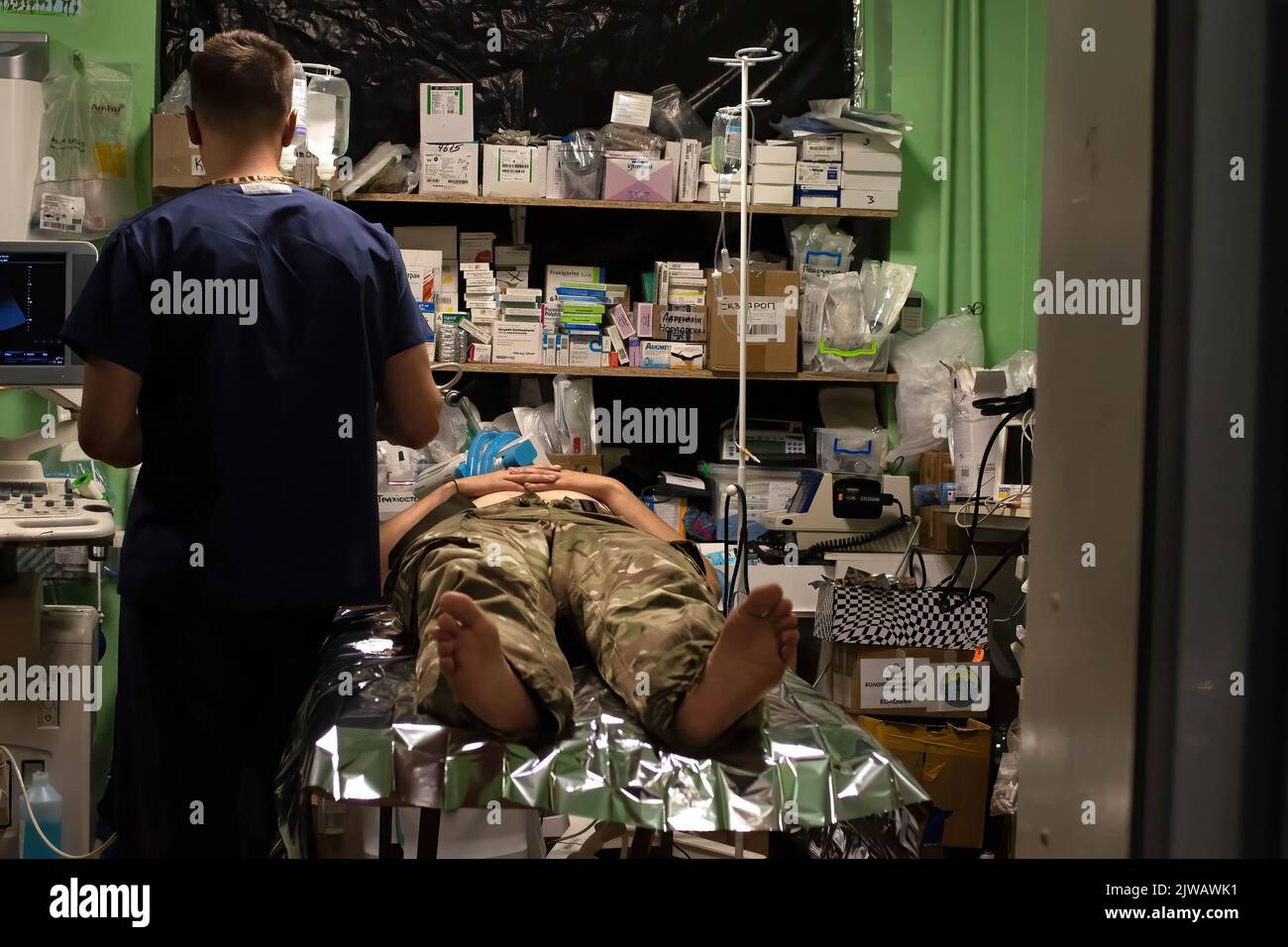 A soldier lies on a stretcher at the traumatology ward while a doctor