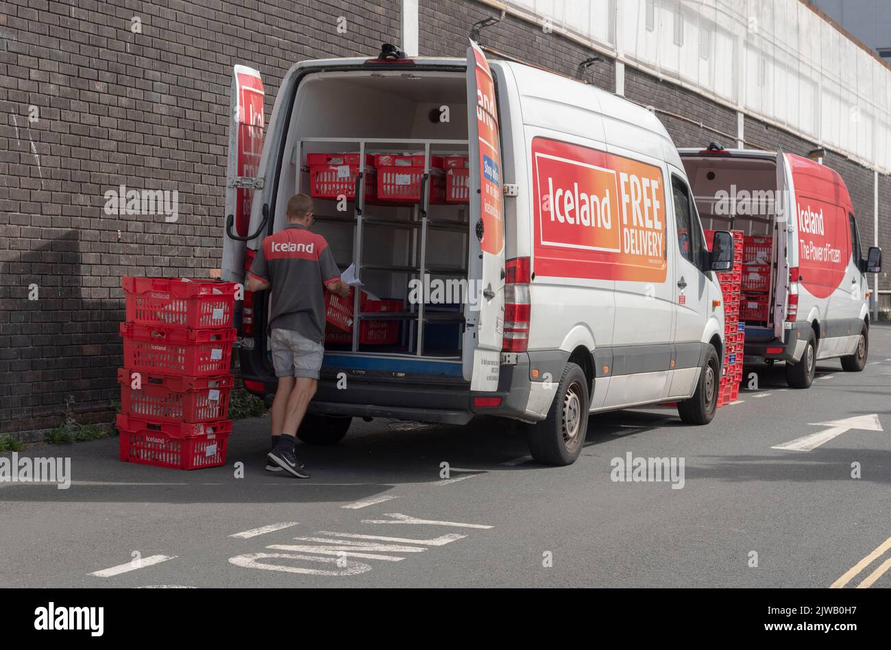 Plymouth, Devon, England, UK. 2022. Grocery and food delivery van being loaded with red plastic boxes by a delivery driver. Stock Photo
