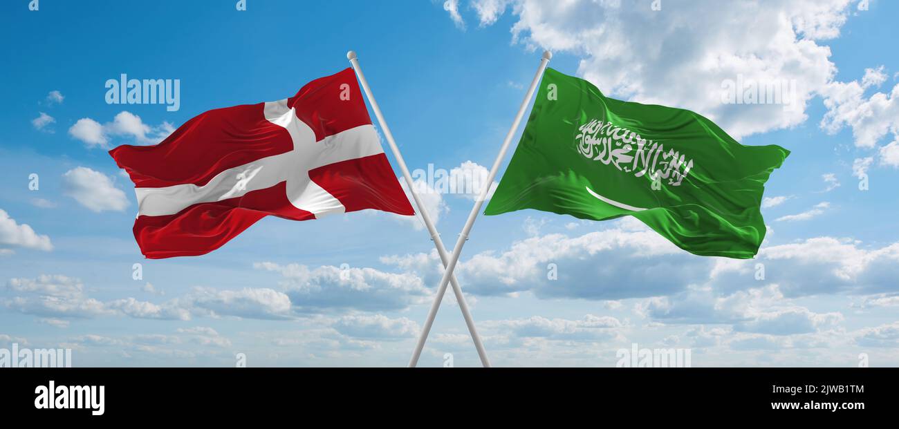 two crossed flags Saudi Arabia and Denmark waving in wind at cloudy sky ...