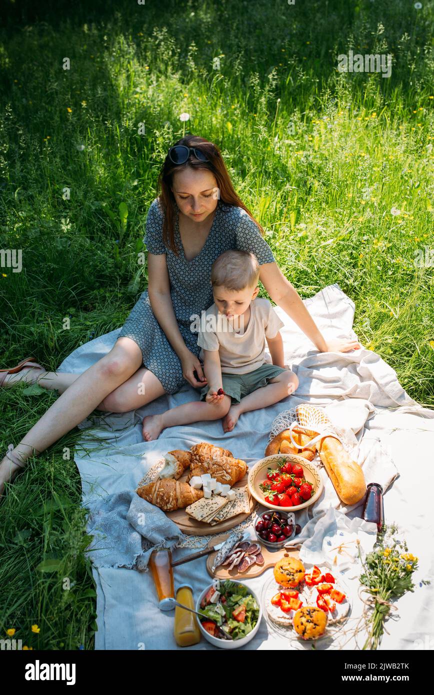 Family mom and son on picnic. Smiling and enjoying summer on blanket in park. Stock Photo