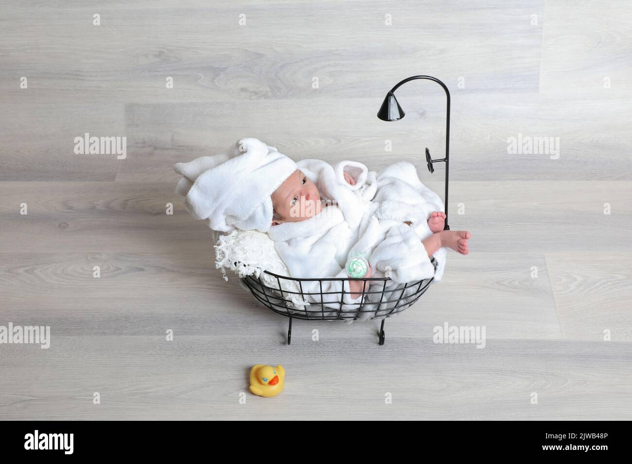 newborn baby boy in white bathrobe laying pose with tiny props shower