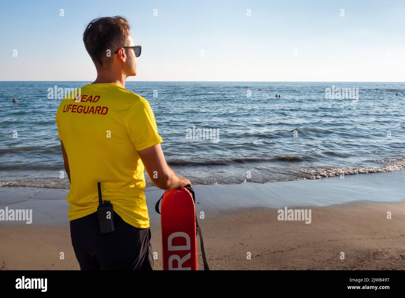 Male lifeguard on the Mediterranean beach watching people in water. Safety while swimming,handsome brunette male lifeguard on the beach. Stock Photo