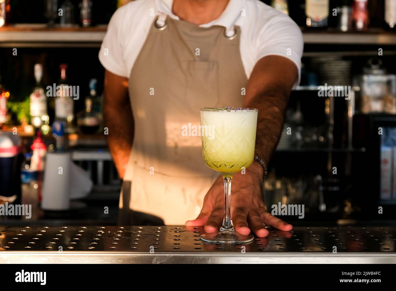 Bartender serving fresh yellow, white summer fruit cocktail at bar counter on sunny day. Selected focus, shallow depth of field. Stock Photo