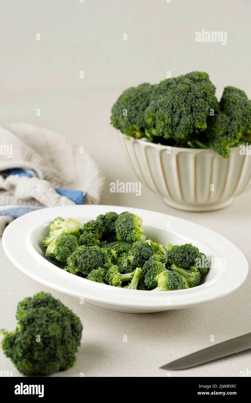 Bunch of Fresh Green Broccoli on White Oval Plate over Cream Background, Copy Space Stock Photo