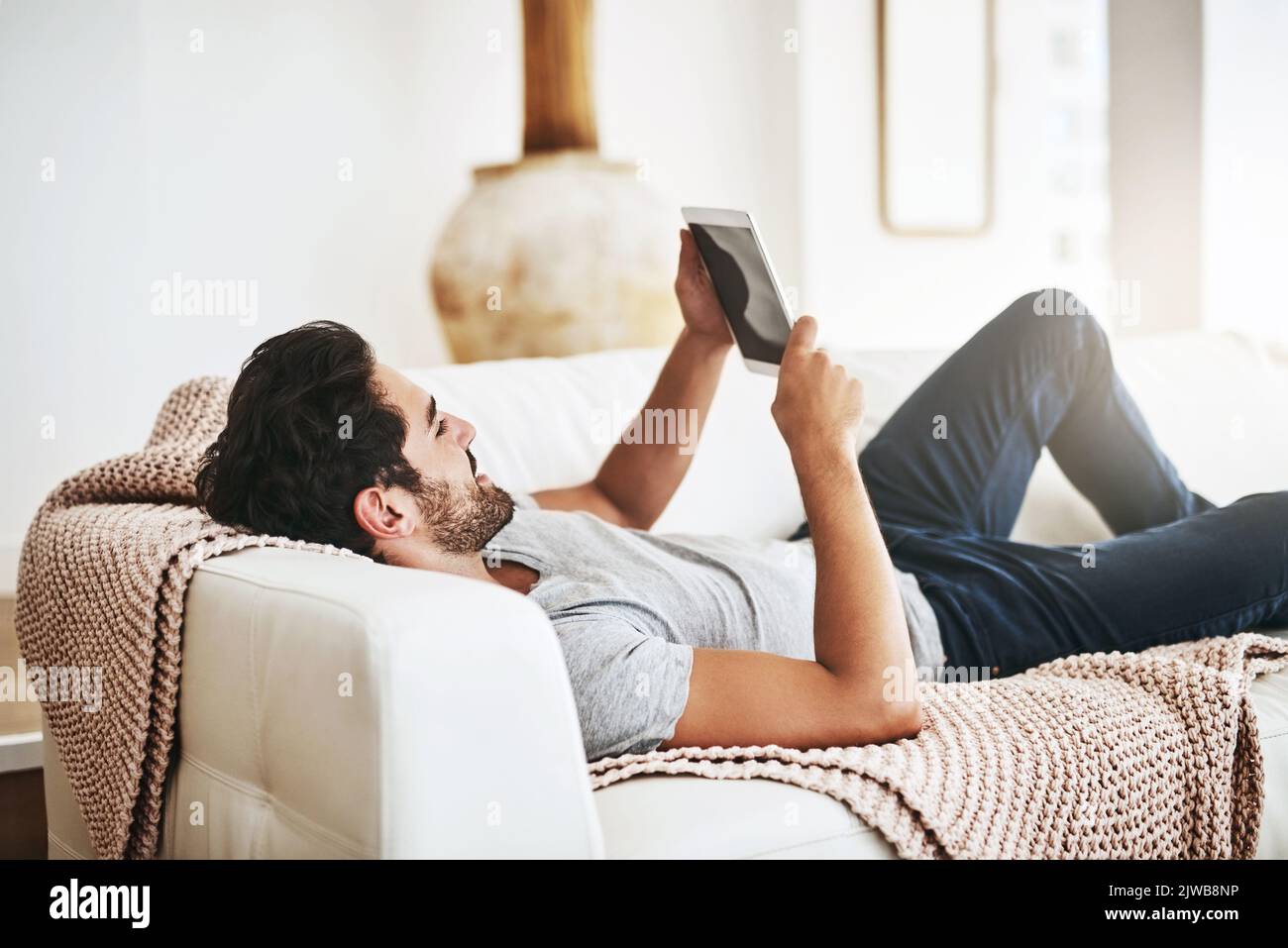 Man Using Devices Enjoying his device at home. a young man using wireless technology on ...