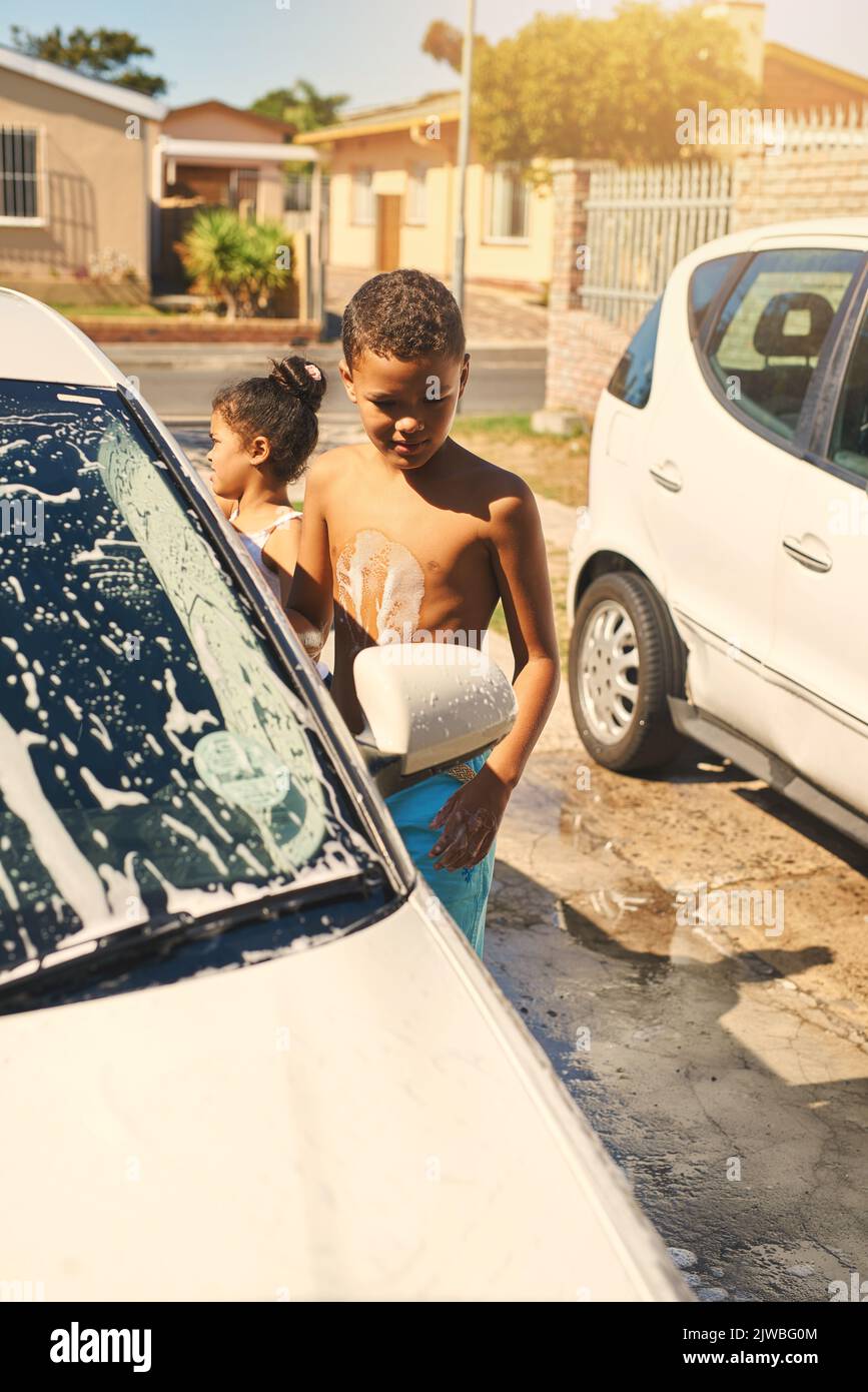Theyre both eager to help. a young boy and girl washing a car together outside. Stock Photo