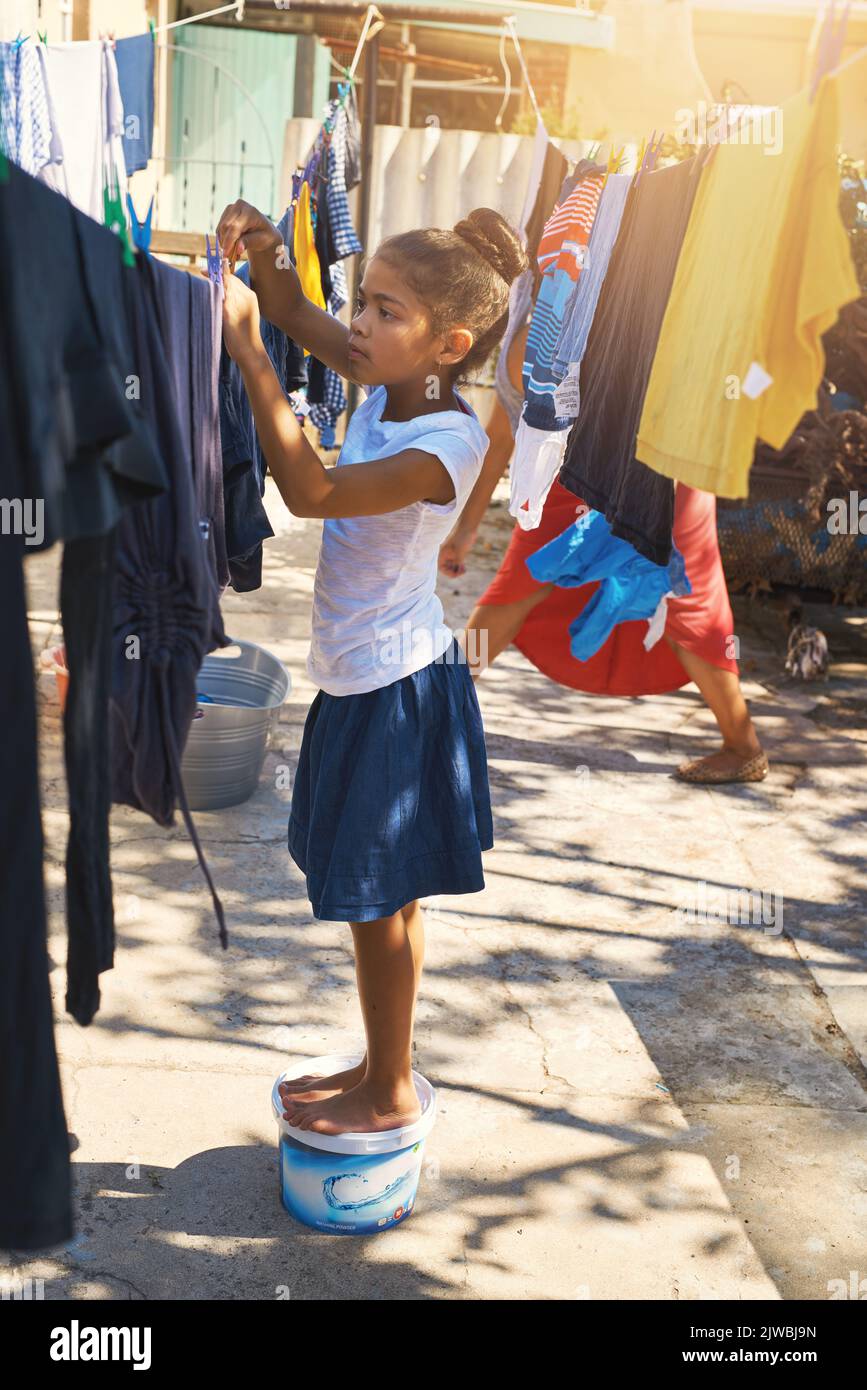 She can do it all by herself. a young girl hanging laundry outside. Stock Photo