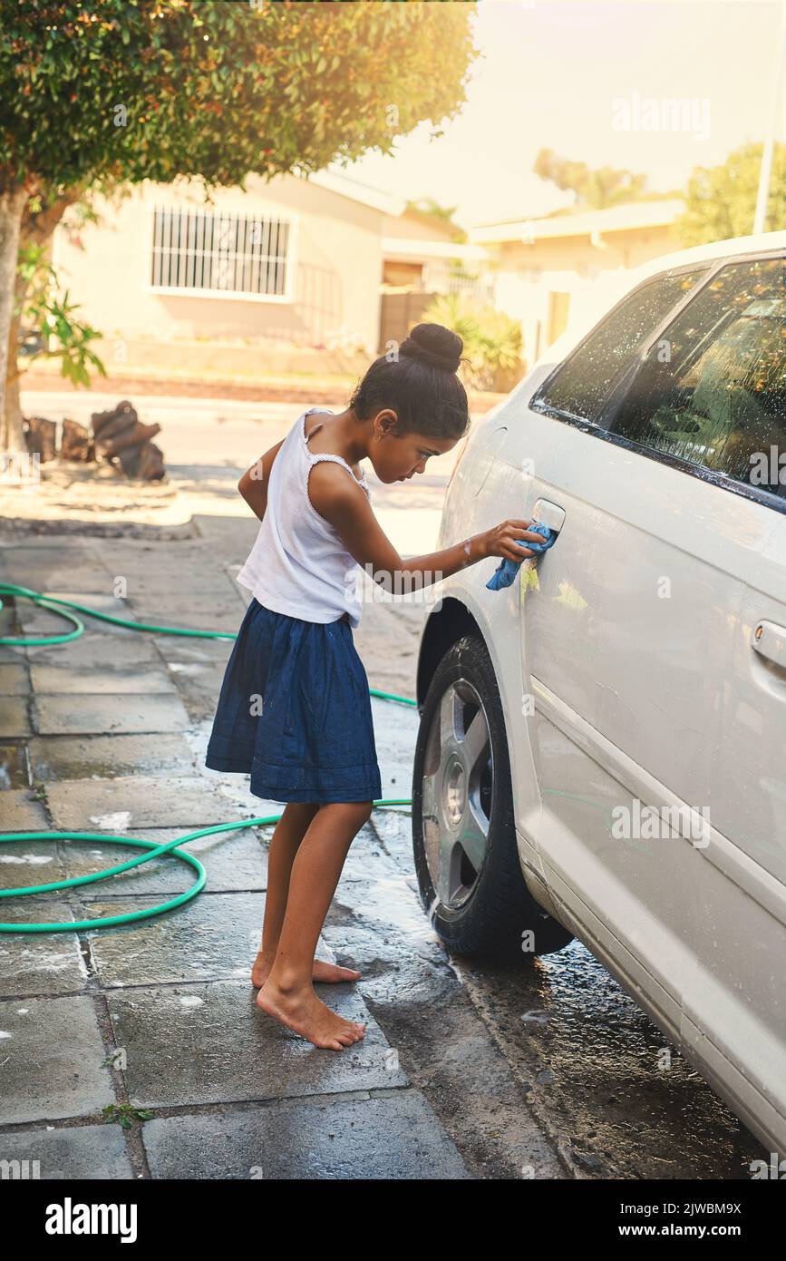 The car will be spotless when shes done. a young girl busy cleaning a car outside. Stock Photo
