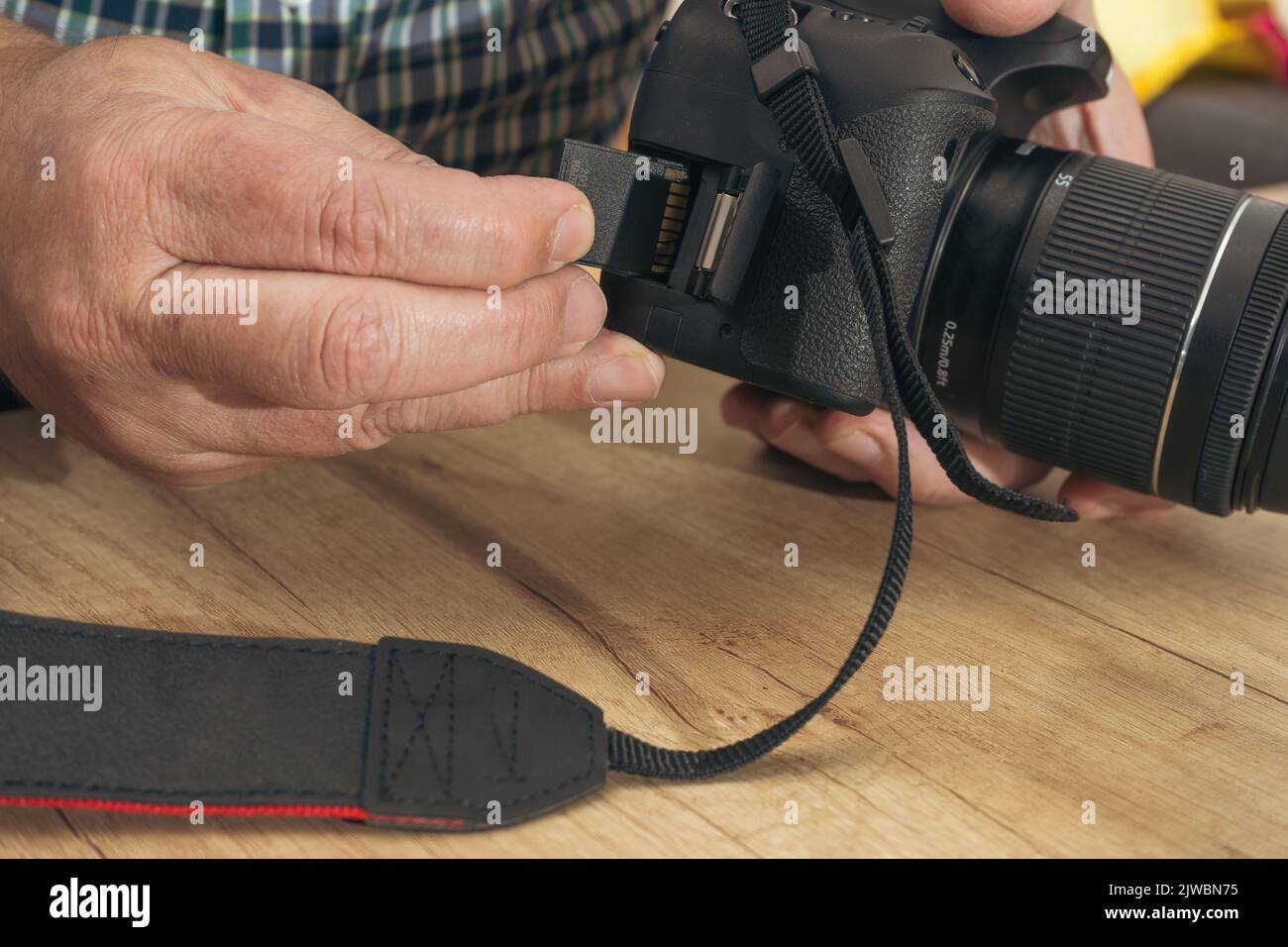 Male photographer inserting a flash memory card while holding a professional camera. Stock Photo