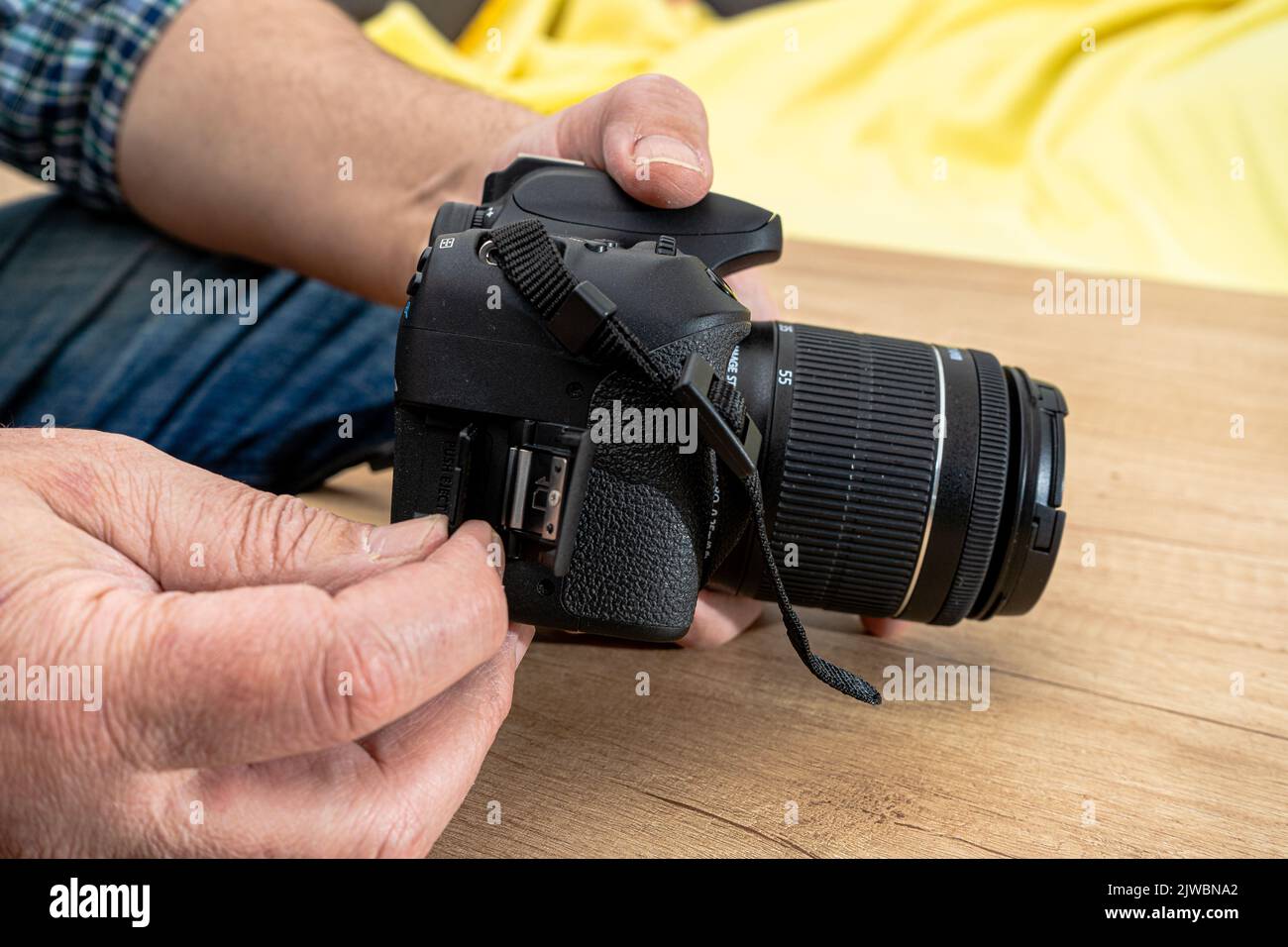 Male photographer inserting a flash memory card while holding a professional camera. Stock Photo