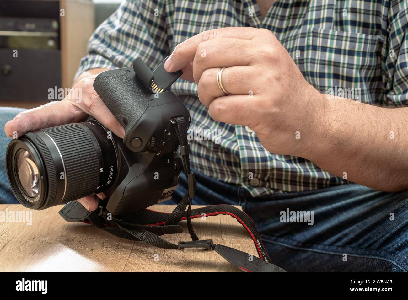 Male photographer inserting a flash memory card while holding a professional camera. Stock Photo