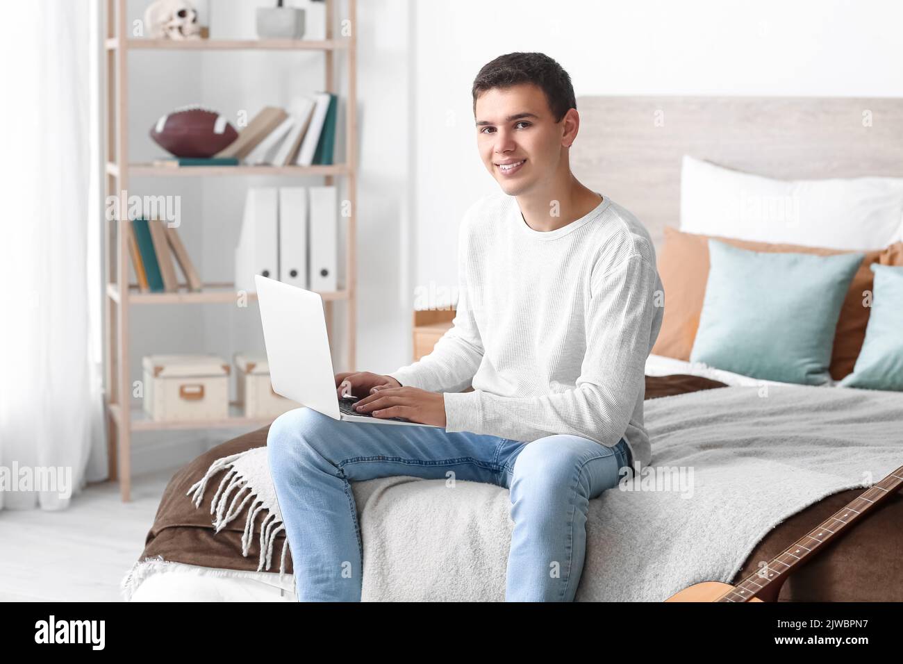 Teenage boy using laptop in bedroom Stock Photo - Alamy