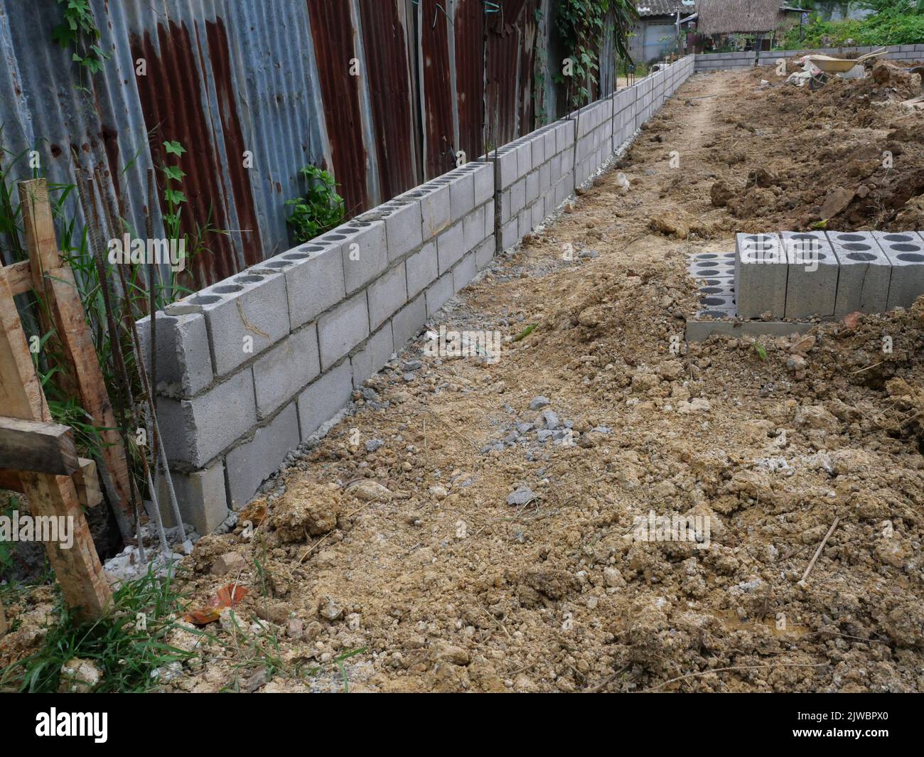 Isometric cinder block wall with steel reinforcement for pillar in construction site on dirt land, Thailand Stock Photo