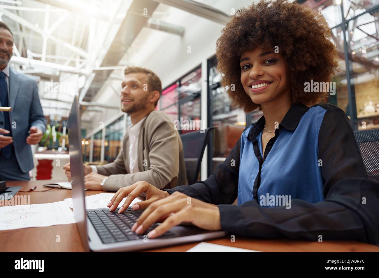 Smiling african businesswoman sitting on his workplace in modern office ...