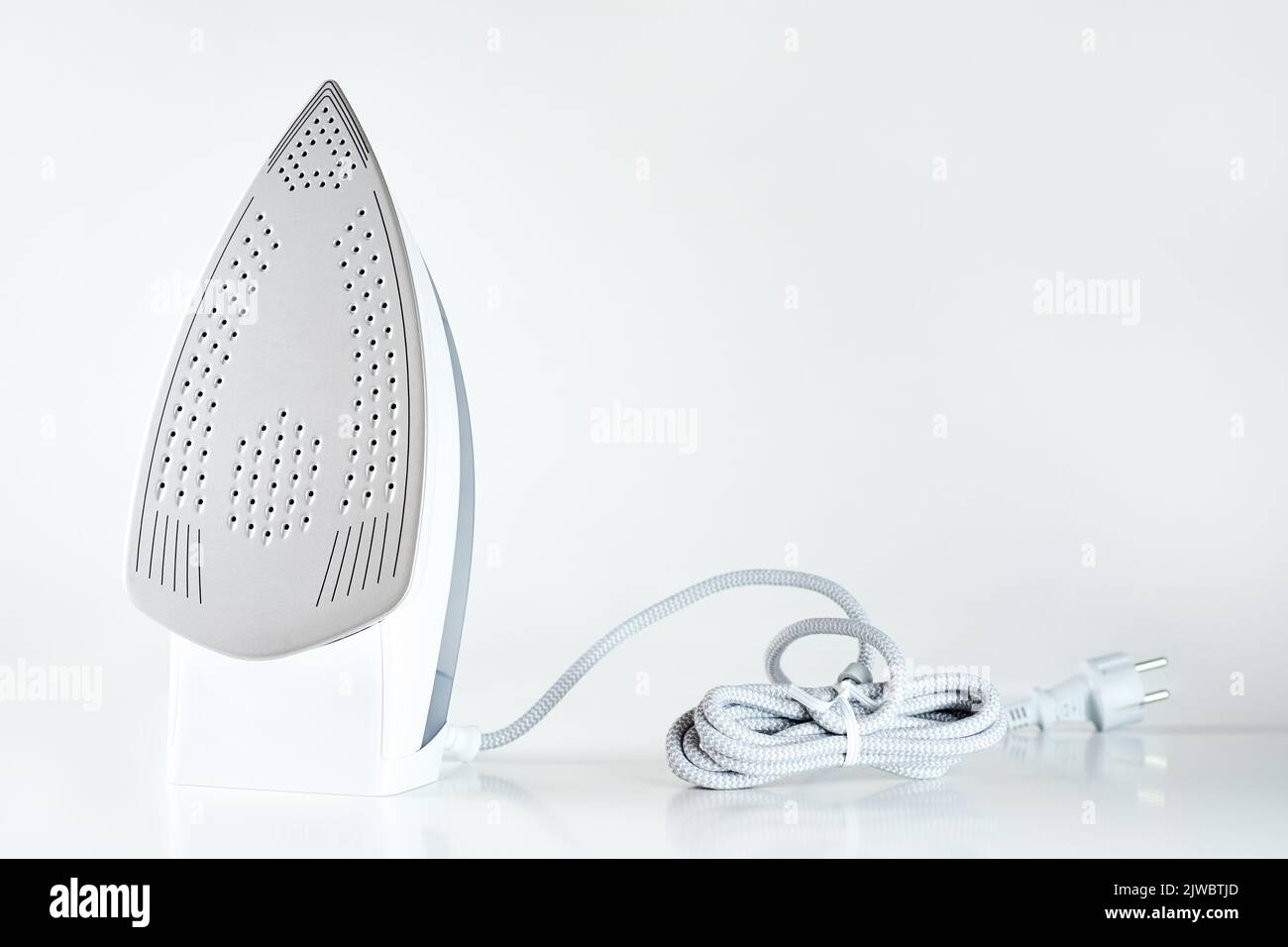 new-iron-with-electrical-cable-on-white-background-modern-household