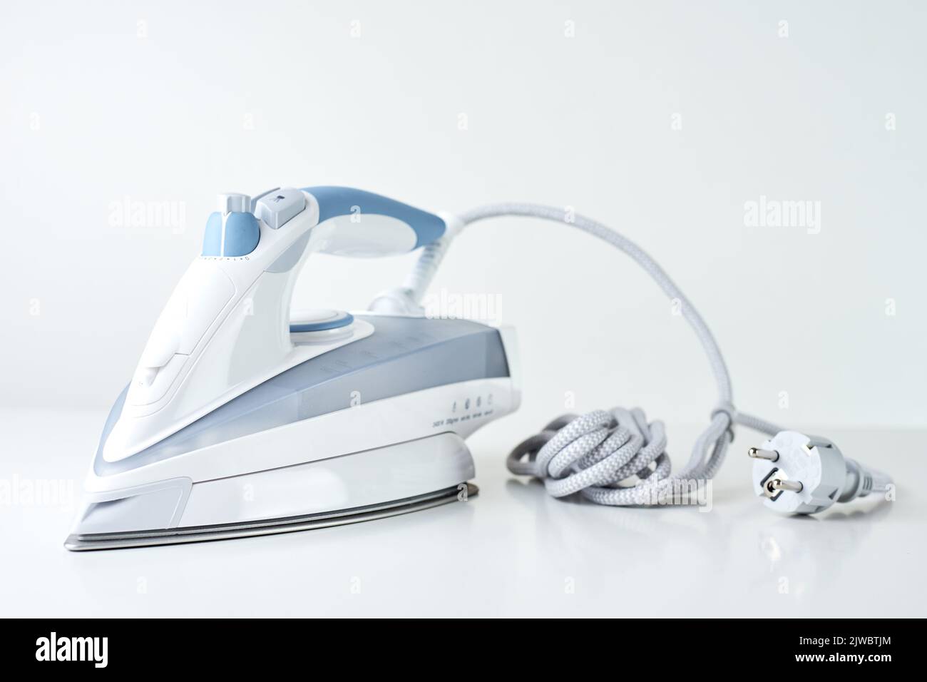 new-iron-with-electrical-cable-on-white-background-modern-household