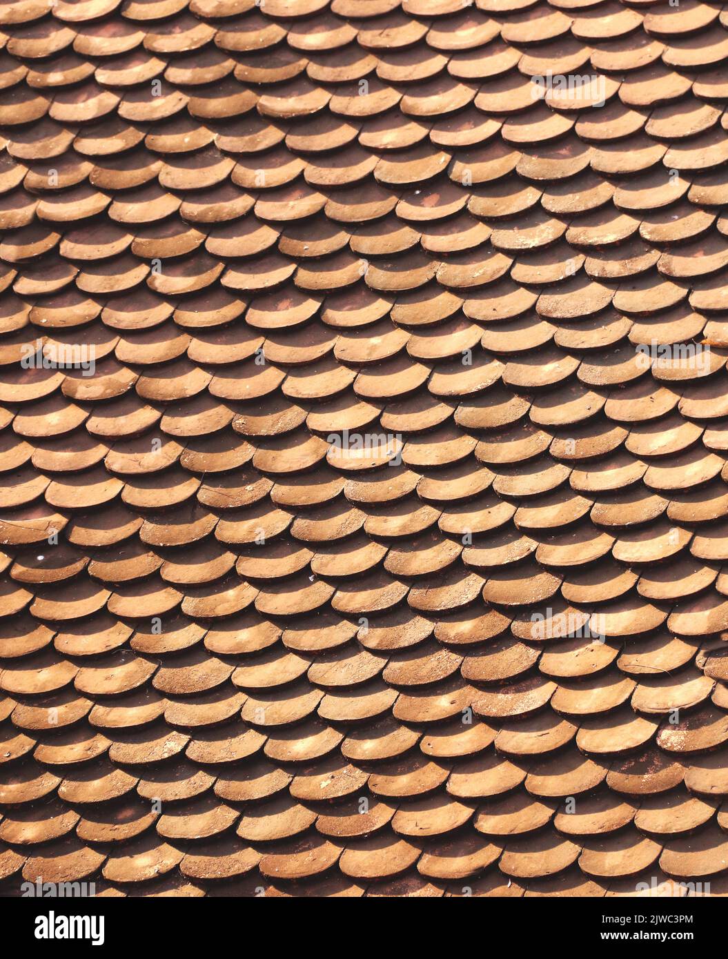 Closeup of clay roof tiles of brown color. Old overlapping classic