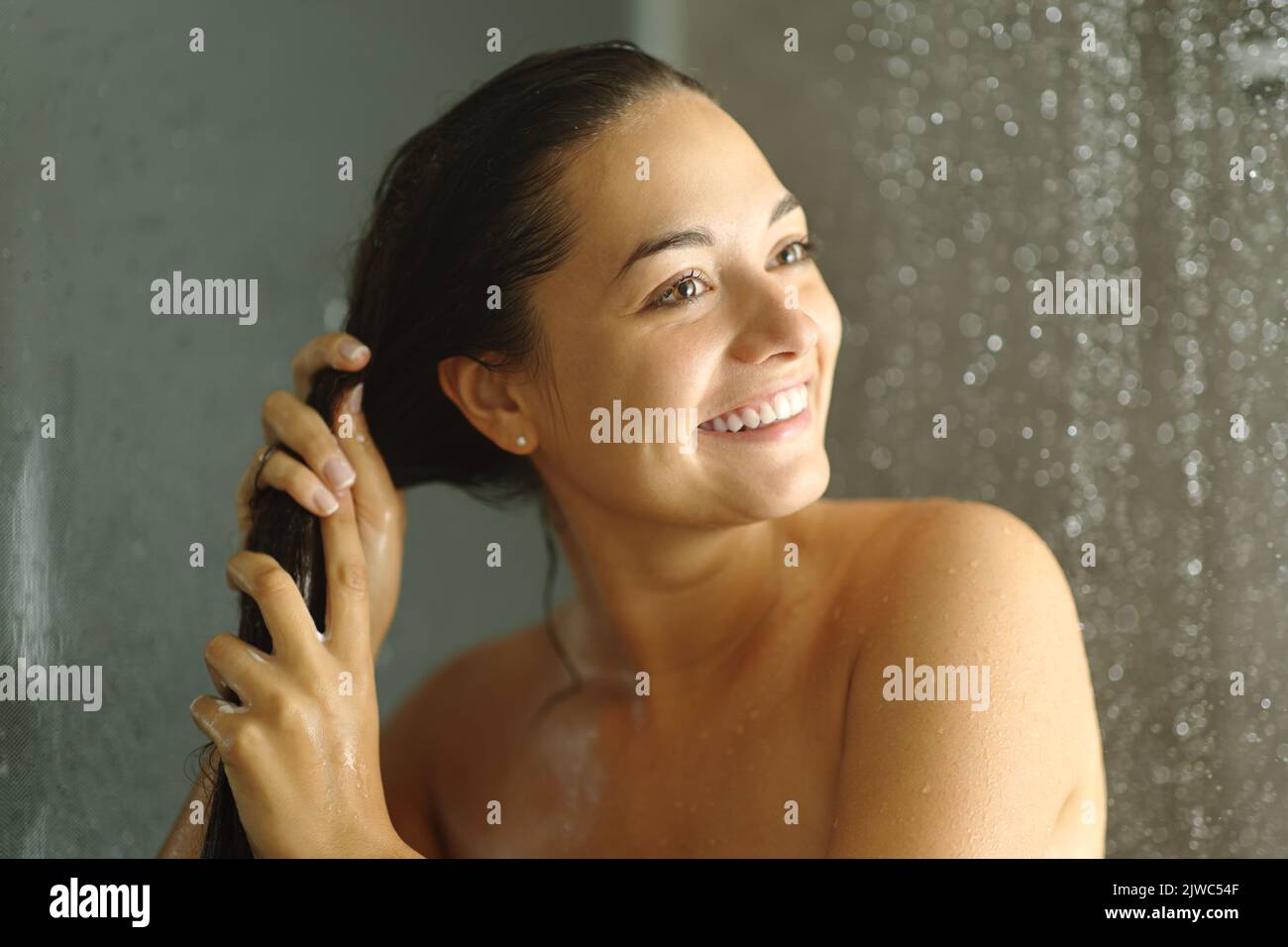 Happy woman washing hair smiling in a shower Stock Photo