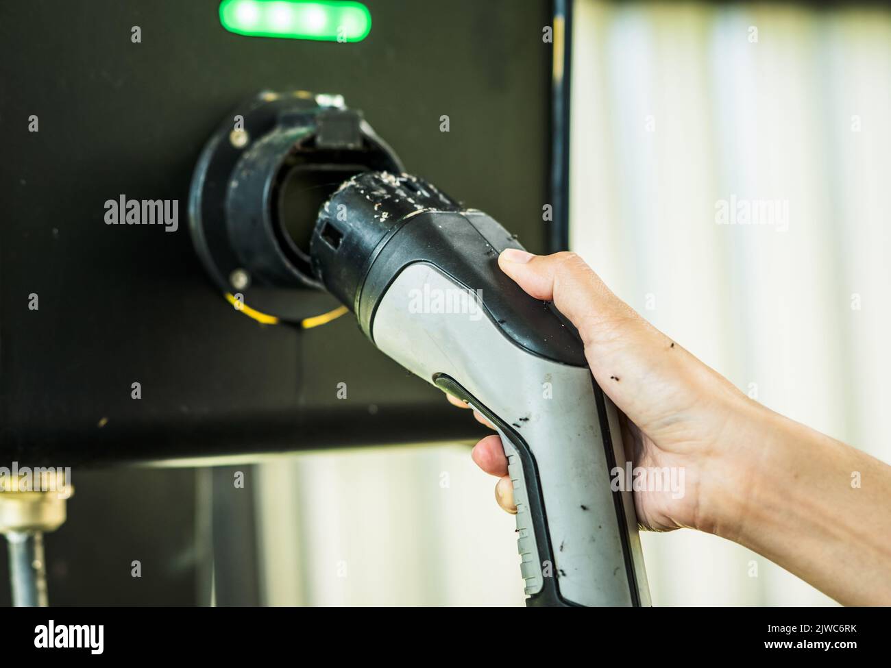 Abandoned electric vehicle charging station. Electric vehicle charging station infrastructure problems. Hand holding EV charger that hasn't been used Stock Photo