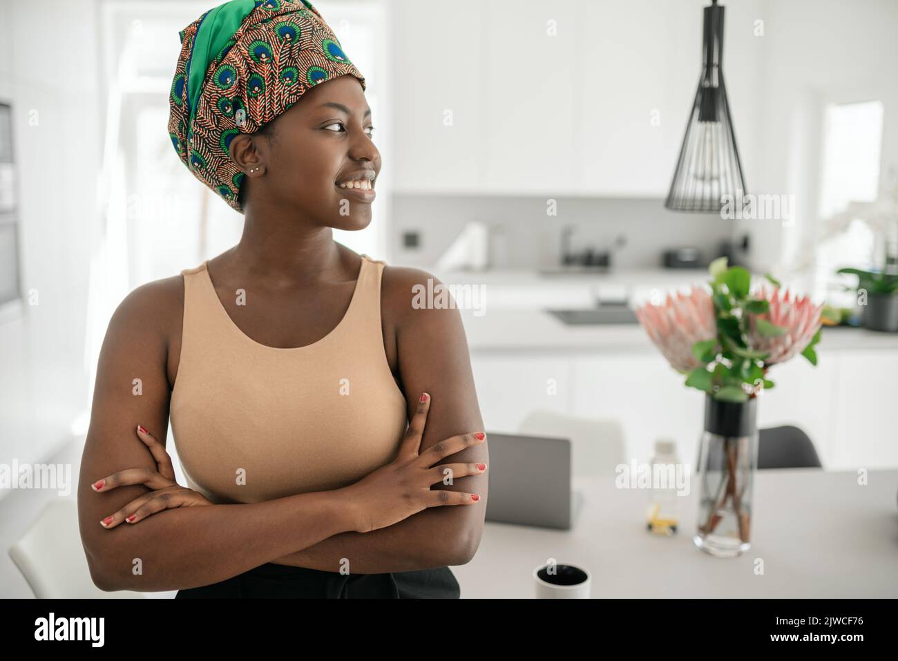 Beautiful African woman at home, smiling , wearing traditional headscarf and looking into distance with copy space Stock Photo