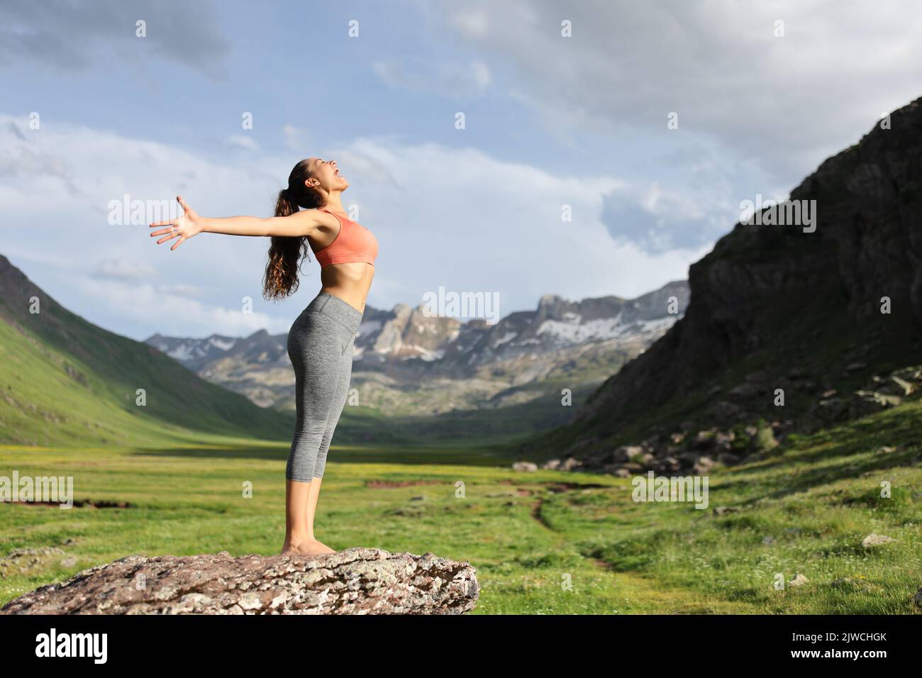 Side view full body portrait of a yogi outstretching arms celebrating in the high mountain Stock Photo