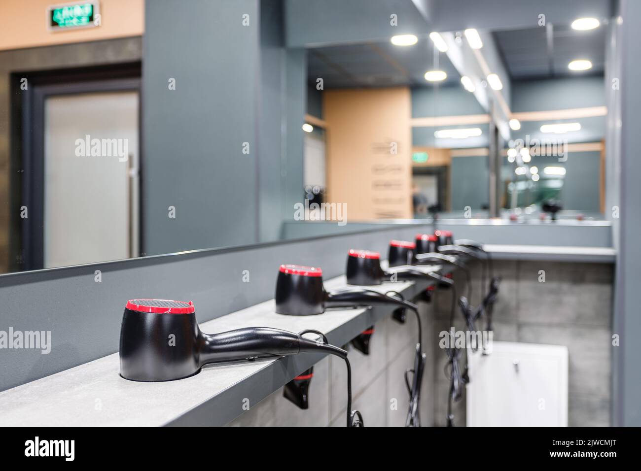 Close up of stand in washroom in gym on which are placed in row many hair dryers. Stock Photo