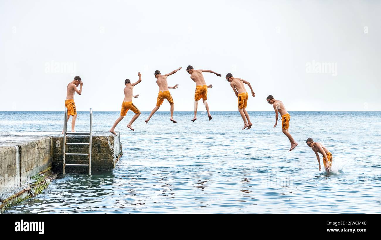 Sequence of jump. Moments of schoolboy jumping from stone pier with ladder into sea doing tricks in combined image sequence Stock Photo