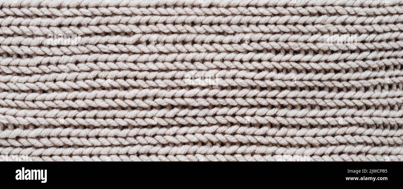 Knitting. Vertical striped beige knit fabric texture, knitted pattern background. Top view, banner. Stock Photo