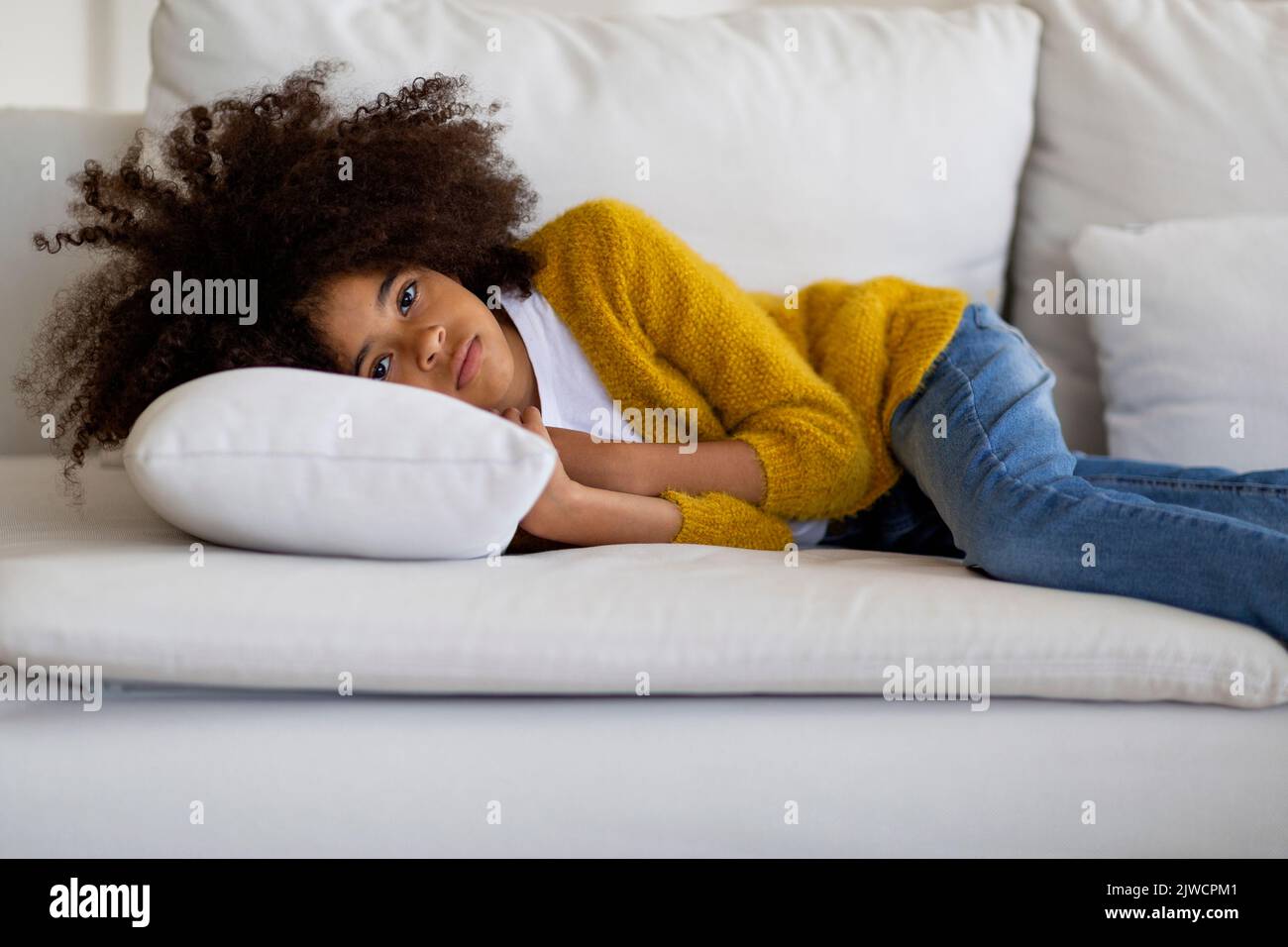 Upset little black girl lying on couch at home Stock Photo - Alamy