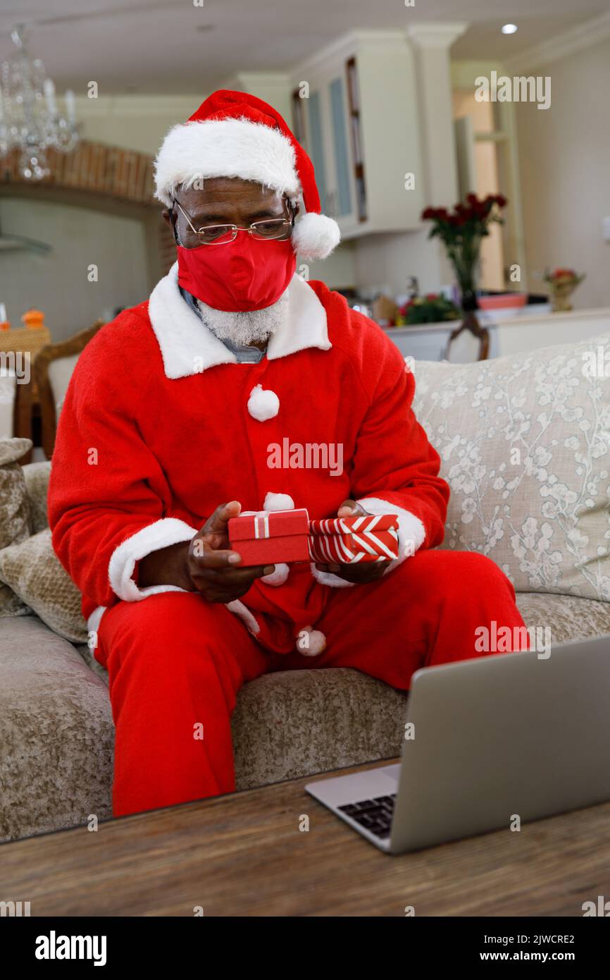 Senior african american man wearing a costume of santa claus and red face mask Stock Photo