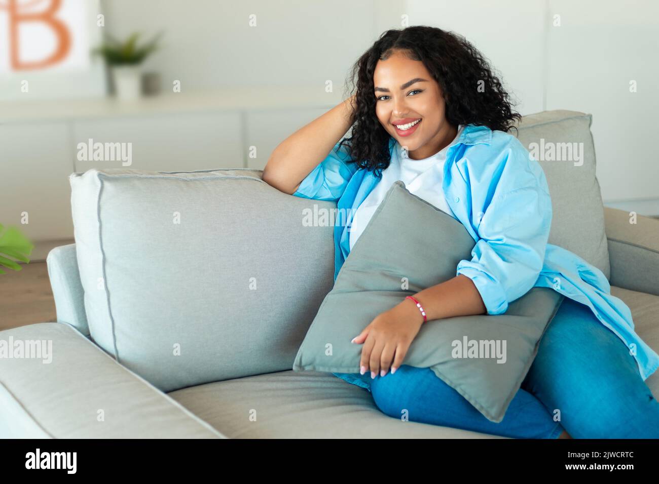 Happy African American Woman Sitting On Sofa At Home Stock Photo - Alamy