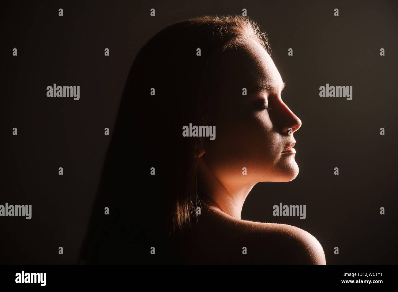 Sensual profile silhouette of woman in trance-like bliss, eyes closed against dramatic dark background