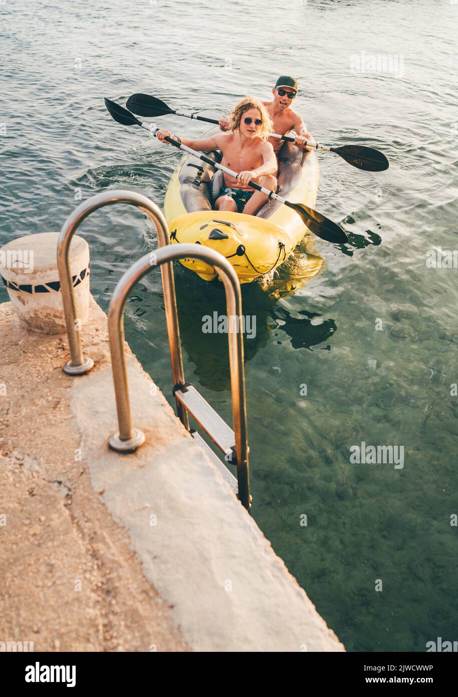 Father with teenager son on the bright yellow inflatable kayak ...