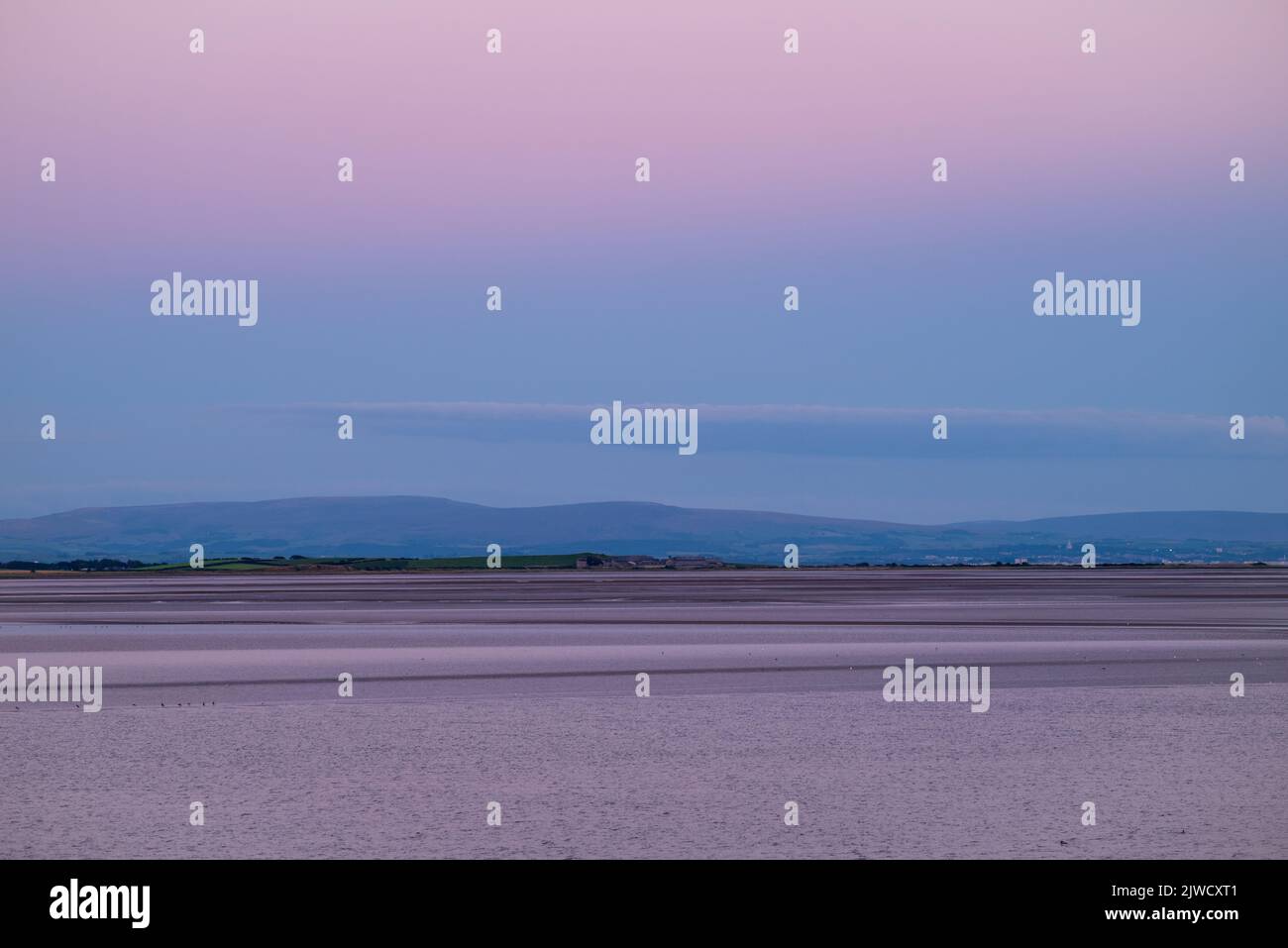 Pink purple hazy sky over Morecambe Bay after sunset. View from Canal Foot, Ulverston, Cumbria, UK Stock Photo