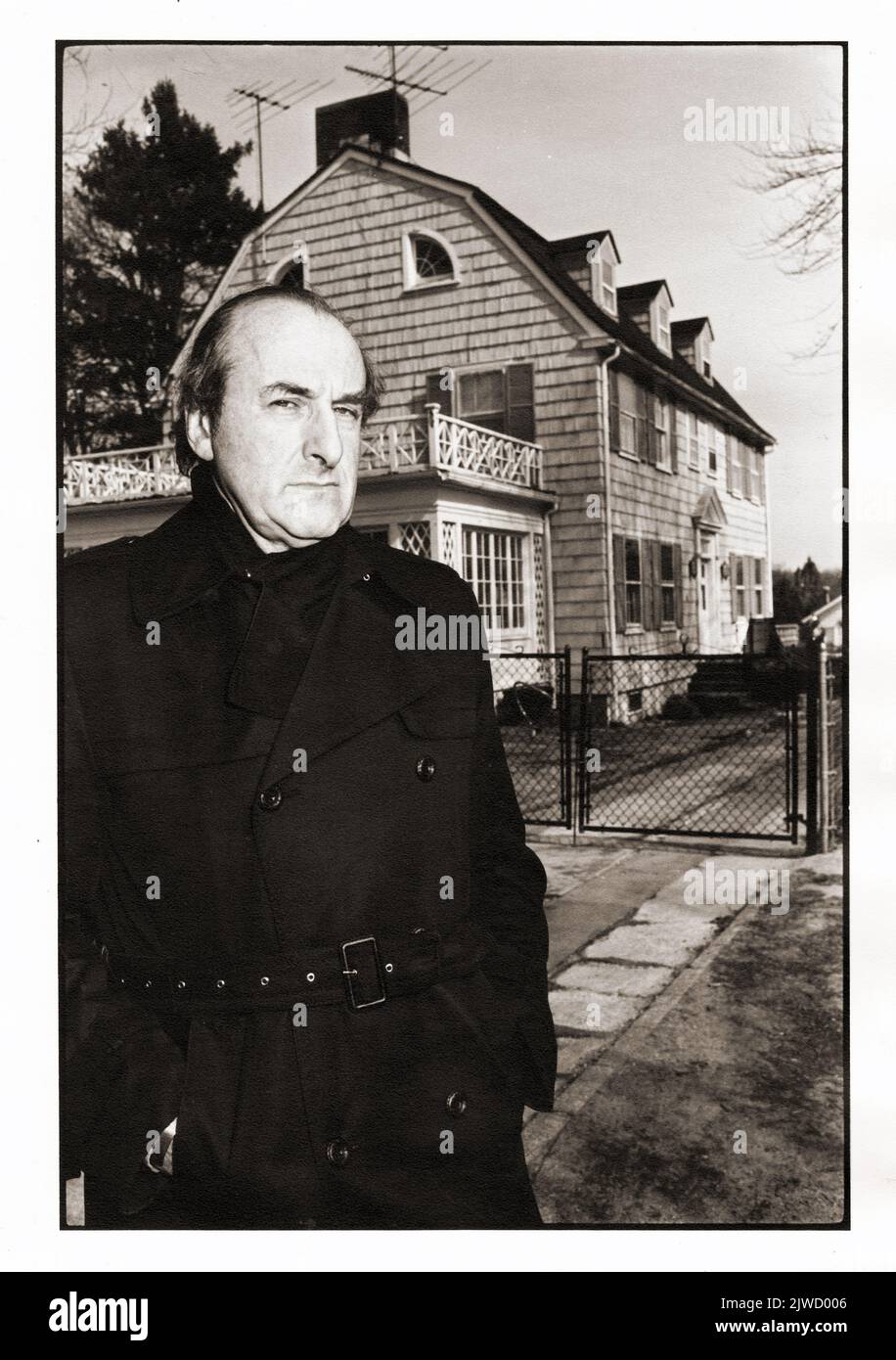 Posed portrait of the late Austrian American author and Parapsychologist Hans Holzer in front of the infamous Amityville Horror House. He investigated the paranormal, ghosts & haunted houses. His book debunked the claims in the popular 1979 move, 'The Amityville Horror.' In Amityville, Long Island, 1980. Stock Photo