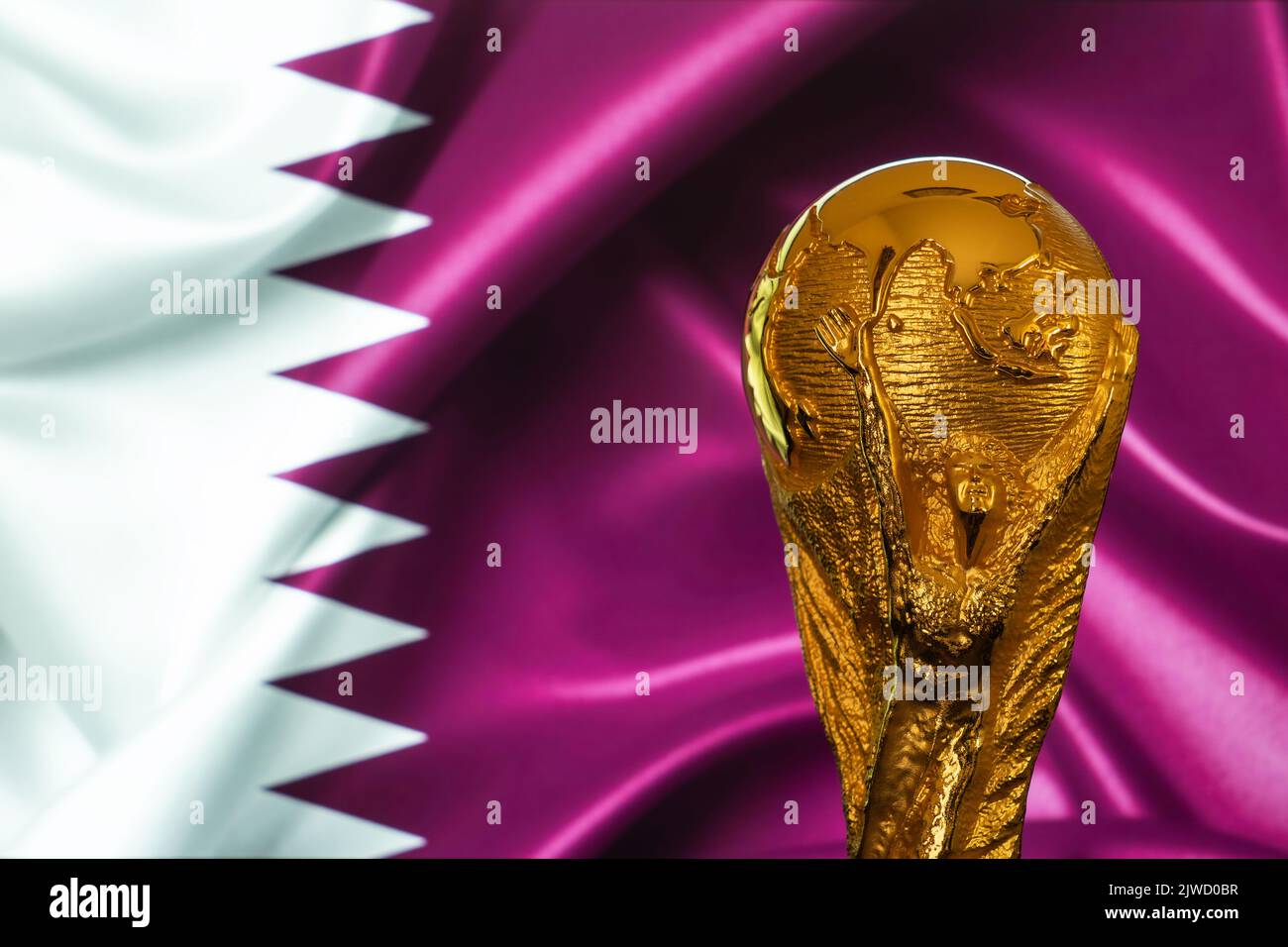 Doha, Qatar - September 4, 2022: FIFA World Cup trophy against the background of Qatar flag. Stock Photo