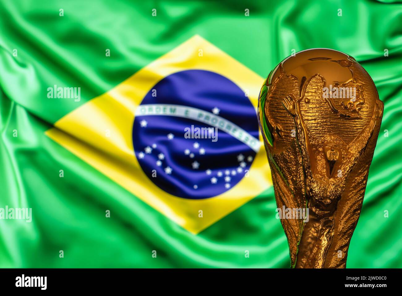 Doha, Qatar - September 4, 2022: FIFA World Cup trophy against the background of Brazil flag. Stock Photo