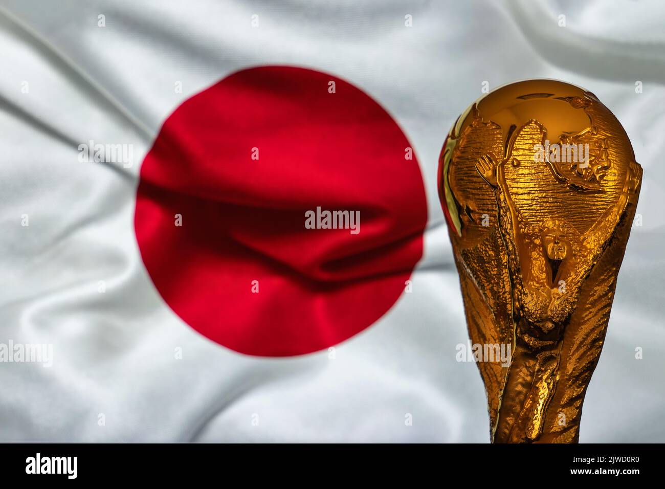 Doha, Qatar - September 4, 2022: FIFA World Cup trophy against the background of Japan flag. Stock Photo
