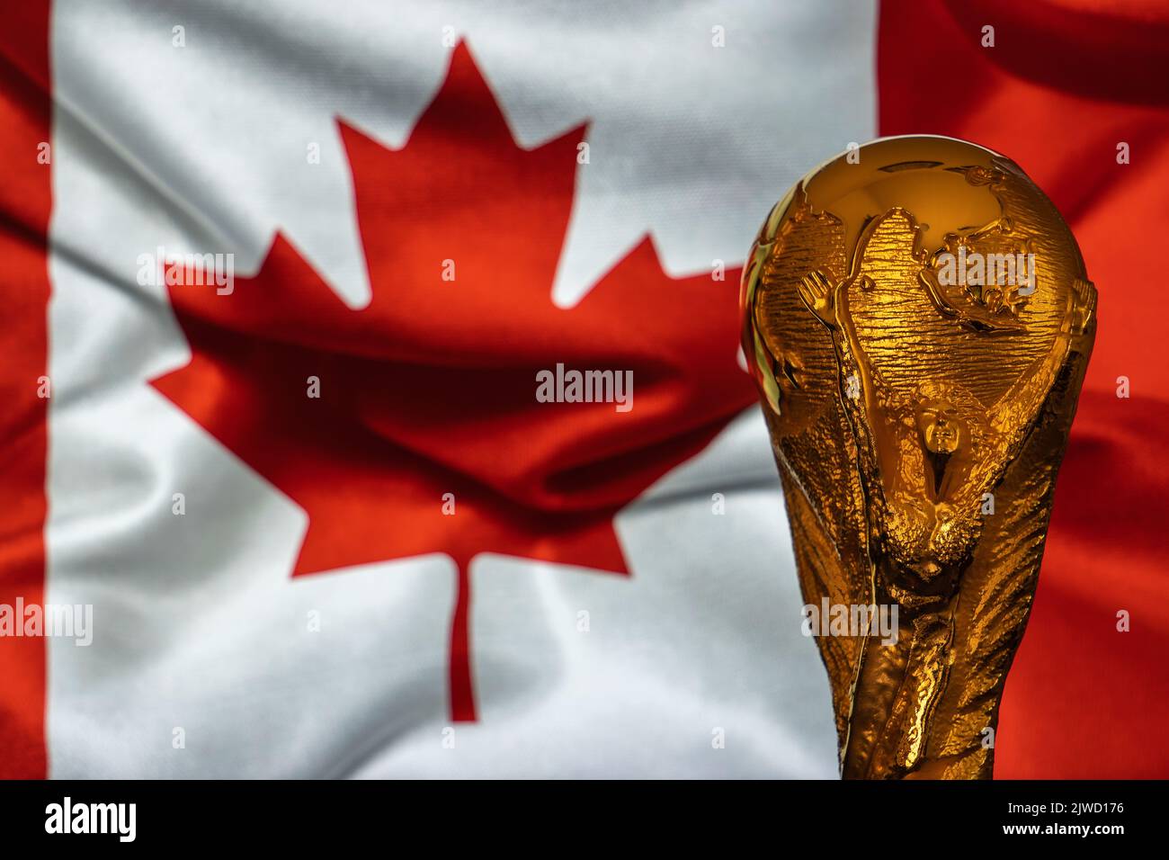 Doha, Qatar - September 4, 2022: FIFA World Cup trophy against the background of Canada flag. Stock Photo