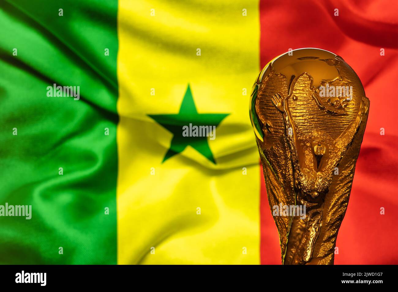 Doha, Qatar - September 4, 2022: FIFA World Cup trophy against the background of Senegal flag. Stock Photo