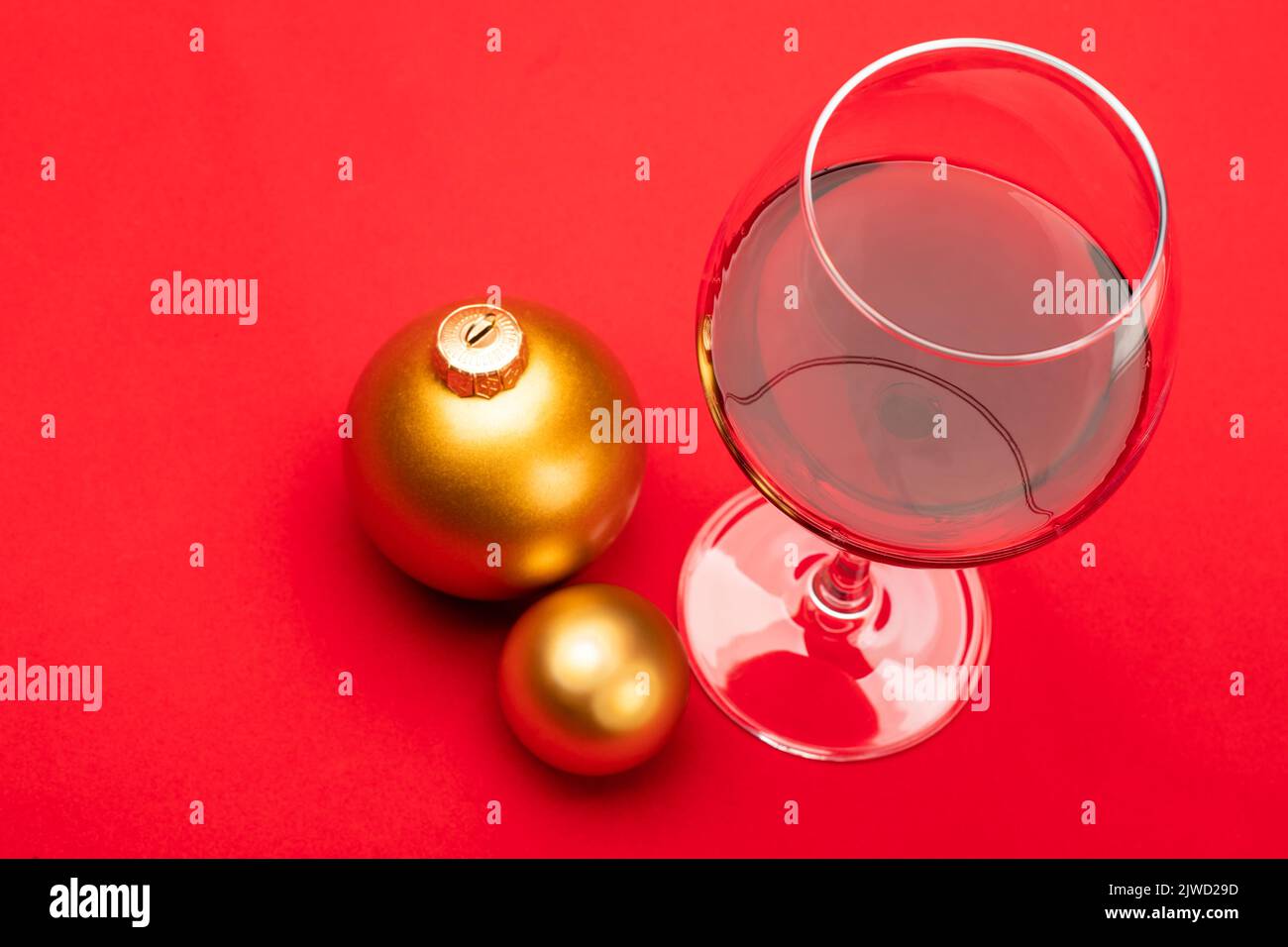 Glass of red wine with christmas baubles on red background - christmas drink concept Stock Photo